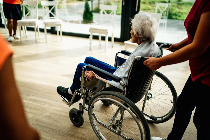 A caregiver assisting an older adult using a wheelchair