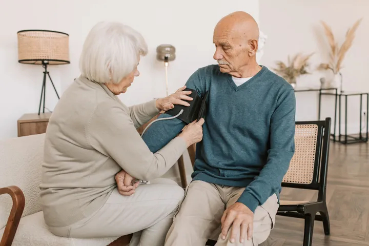 A caregiver checking blood pressure for an older adult at home
